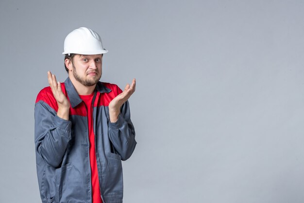 front view male builder in uniform confused on light background