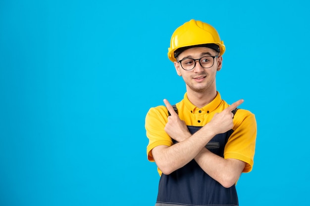 Vista frontale del costruttore maschio in uniforme e casco sulla superficie blu