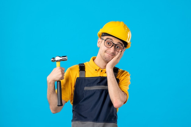Front view of male builder in uniform and helmet on blue surface