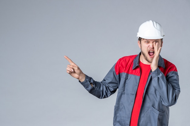 Free photo front view male builder in uniform and helmet on gray background