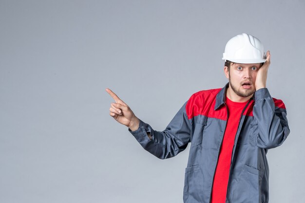 front view male builder in uniform and helmet on gray background