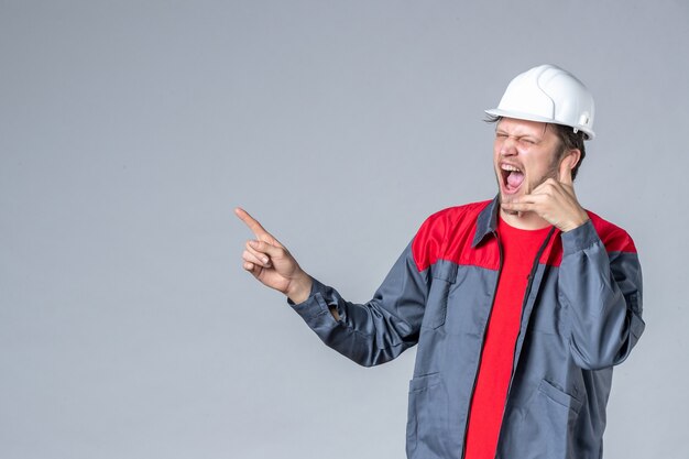 front view male builder in uniform and helmet on gray background