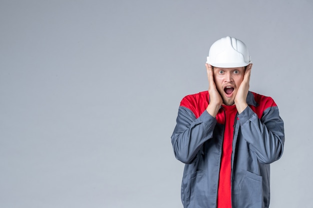 front view male builder in uniform and helmet on gray background