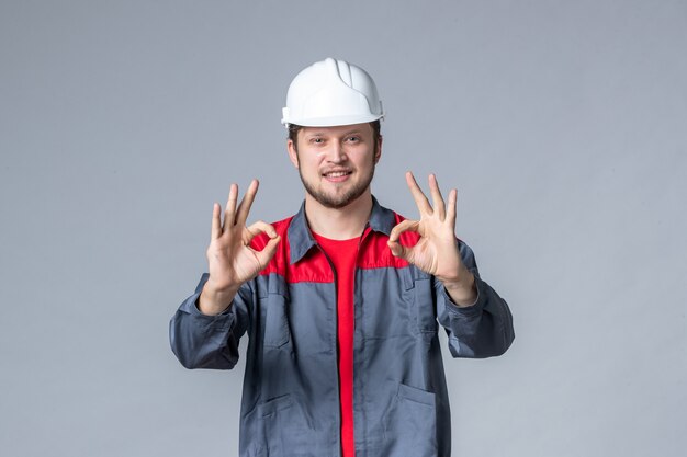 вид спереди мужчина-строитель в форме и шлеме на сером фоне