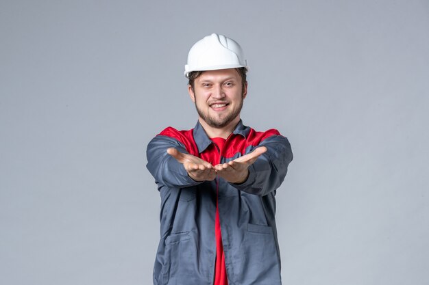 front view male builder in uniform and helmet on gray background