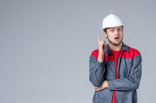 front view male builder in uniform and helmet on gray background