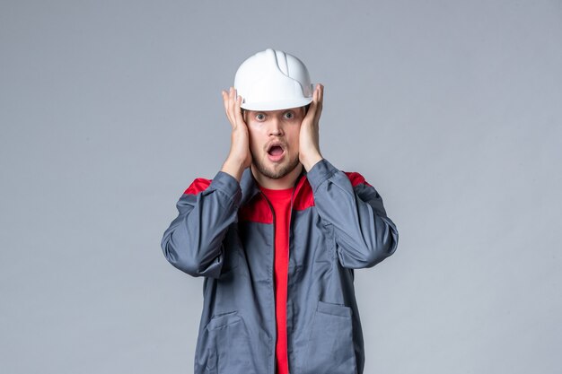 front view male builder in uniform and helmet on gray background