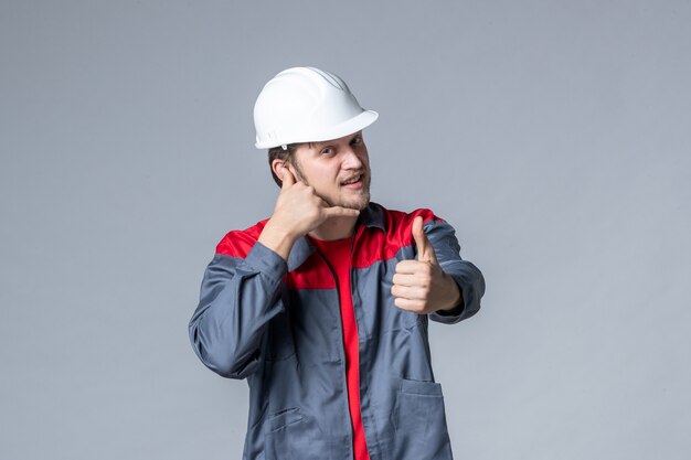 front view male builder in uniform and helmet on gray background