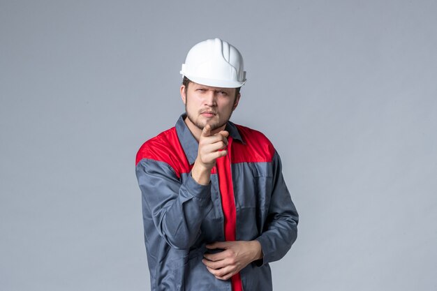 front view male builder in uniform and helmet on gray background