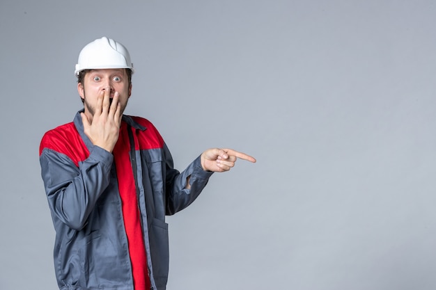 front view male builder in uniform and helmet on light background