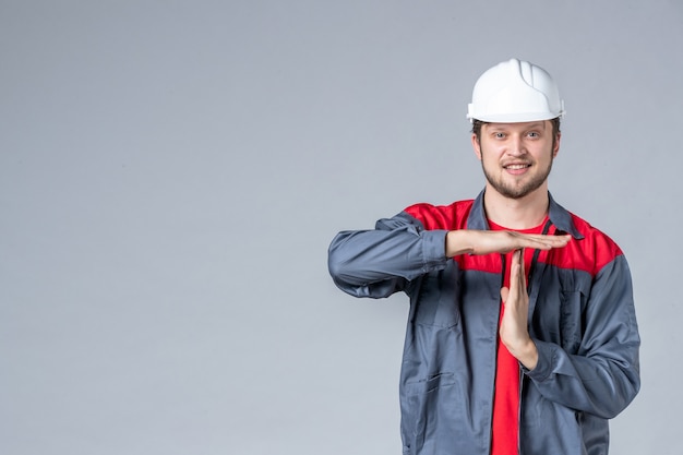 front view male builder in uniform and helmet on light background