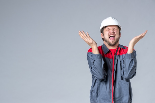 front view male builder in uniform and helmet on light background