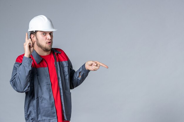 front view male builder in uniform and helmet on light background