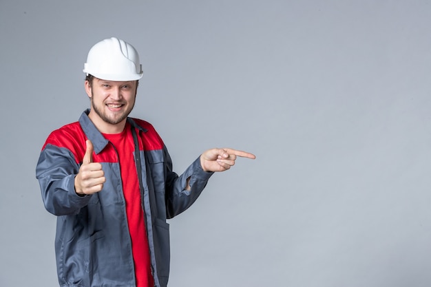 Мужчина-строитель в униформе, вид спереди, демонстрирует удивительный жест на светлом фоне