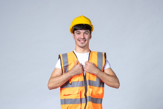 Vista frontale del costruttore maschio in uniforme sul muro bianco