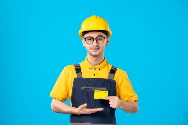 Free photo front view of male builder in uniform with bank card in his hands on a blue wall