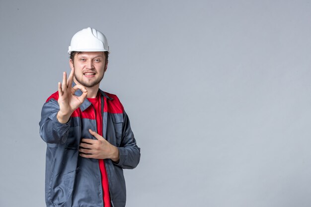 front view male builder in uniform with delighted face on light background