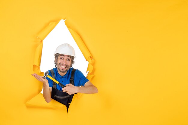 노란색 벽 색상 작업자 작업 생성자 건물 남자에 망치로 제복을 입은 전면 보기 남성 빌더