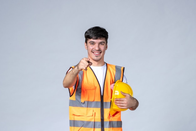 вид спереди мужчины-строителя в форме с защитным шлемом на белой стене