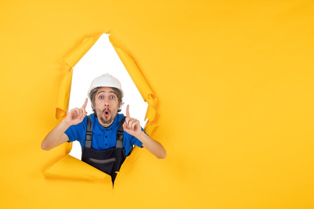 Front view male builder in uniform on a yellow background