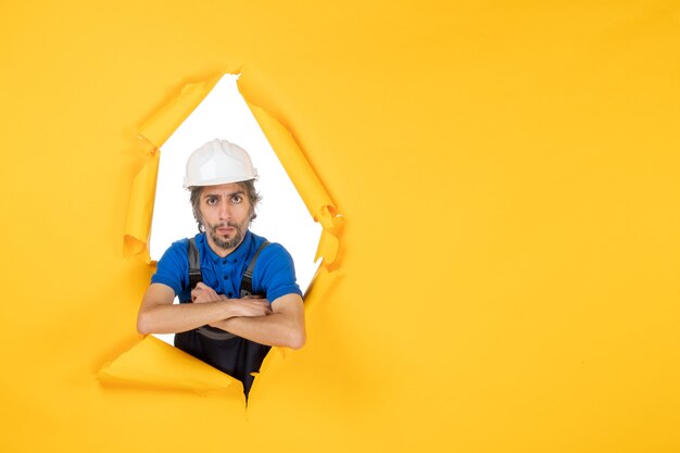 Front view male builder in uniform on a yellow background