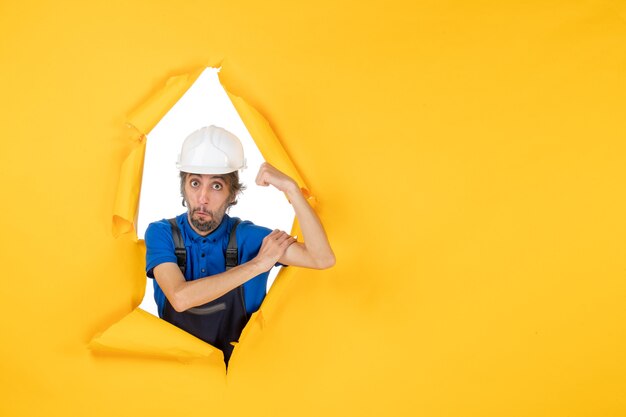 Free photo front view male builder in uniform on the yellow background