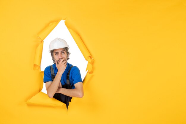 Мужчина-строитель в униформе на желтом фоне, вид спереди