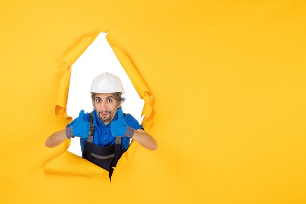 front view male builder in uniform on yellow background