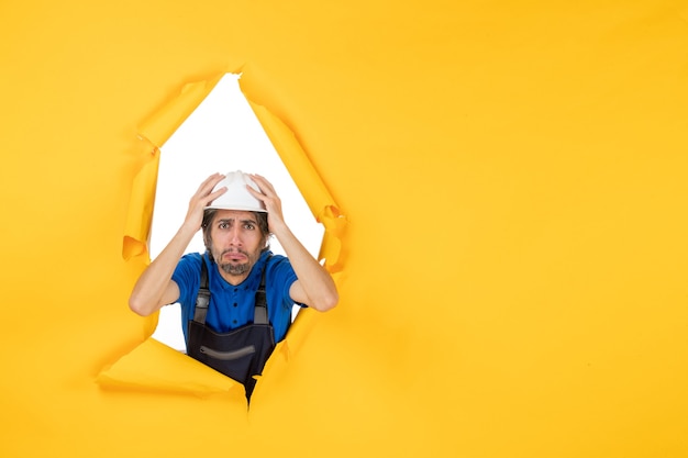 Front view male builder in uniform on yellow background