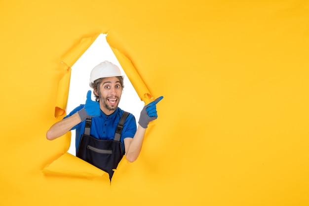 Front view male builder in uniform on yellow background