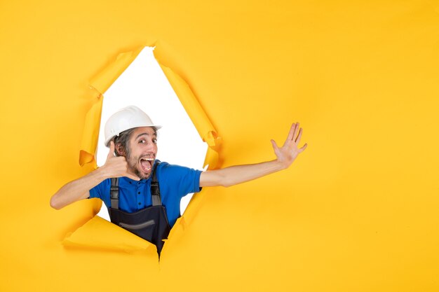 front view male builder in uniform on yellow background