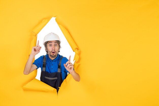 front view male builder in uniform on yellow background