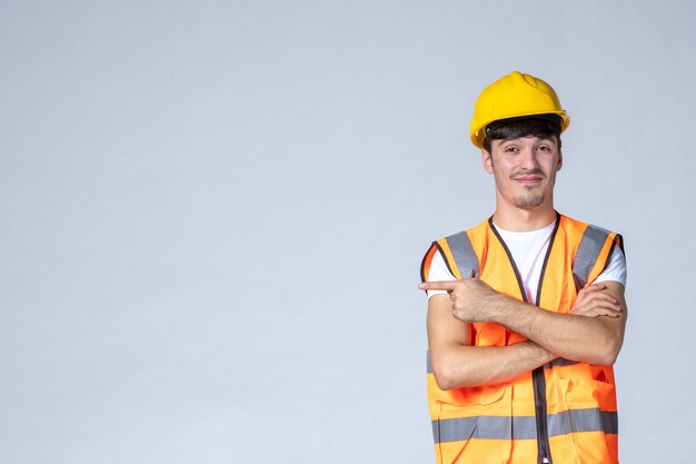 front view male builder in uniform and yellow helmet on grey wall