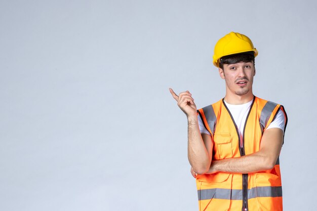 front view male builder in uniform and yellow helmet on white wall