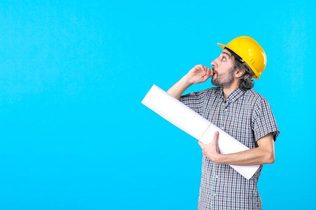 Строитель-мужчина, вид спереди с планом на руках на синем фоне, инженер, рабочий, конструктор, работа, недвижимость, архитектура, здание