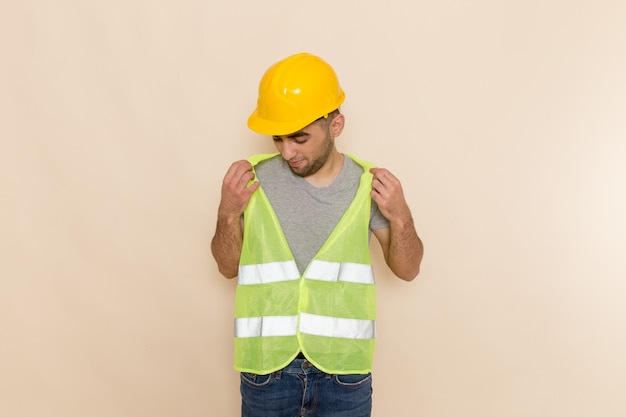 Вид спереди мужчина-строитель в желтом шлеме, просто стоя на светлом фоне