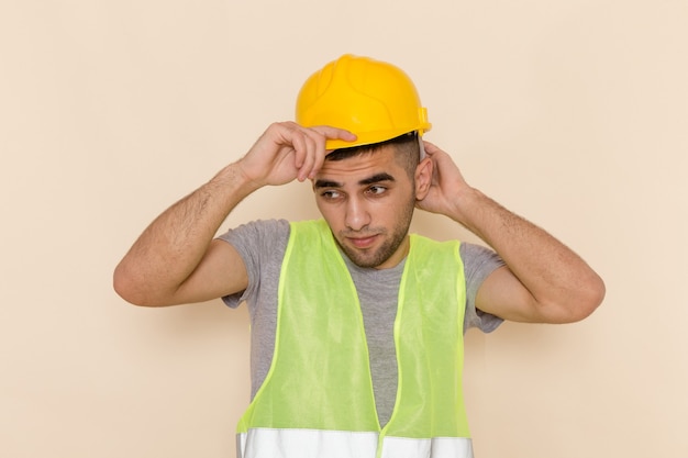 Front view male builder in yellow helmet posing on light background