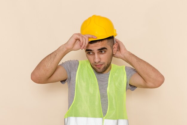 Front view male builder in yellow helmet posing on light background