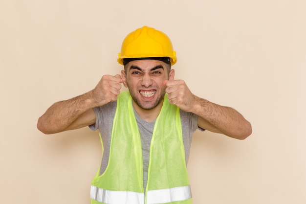 Free photo front view male builder in yellow helmet posing with excited expression on light background