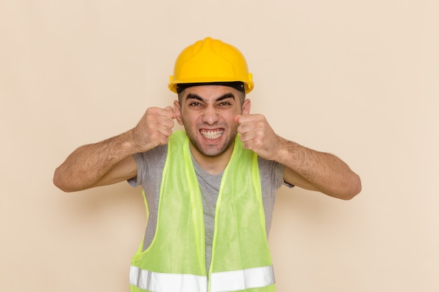 Front view male builder in yellow helmet posing with excited expression on light background