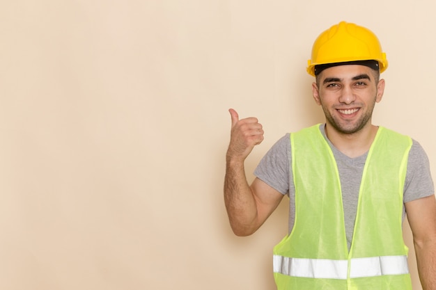 Free photo front view male builder in yellow helmet posing with a smile on the light background