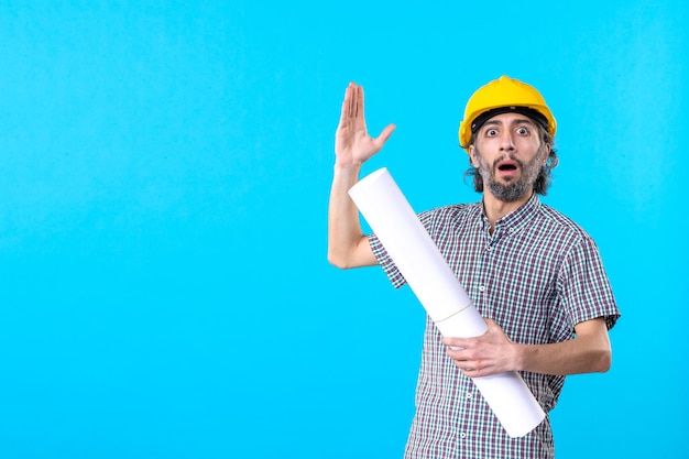 Front view male builder in yellow helmet with plan on blue background worker architecture constructor building colors flat property