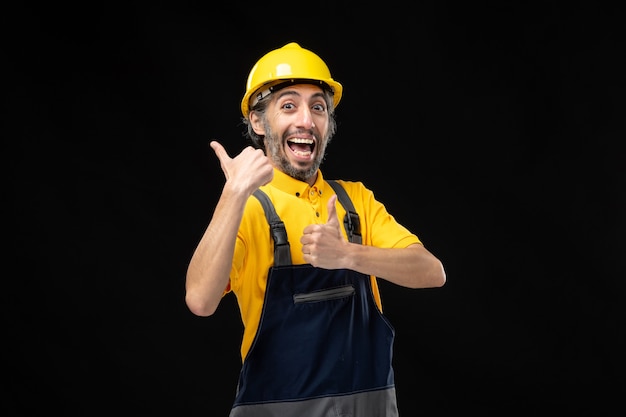 Front view of male builder in yellow uniform on black wall