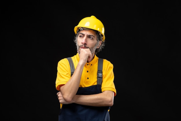 Front View of Male Builder in Yellow Uniform on Black Wall