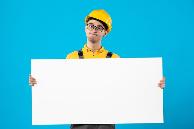 Front view of male builder in yellow uniform on blue 