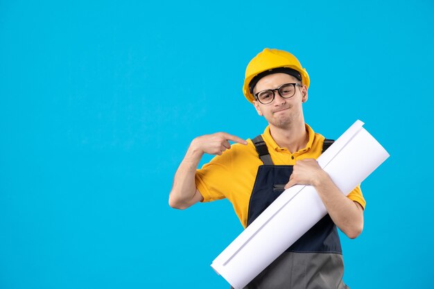 Front view male builder in yellow uniform and helmet on blue 