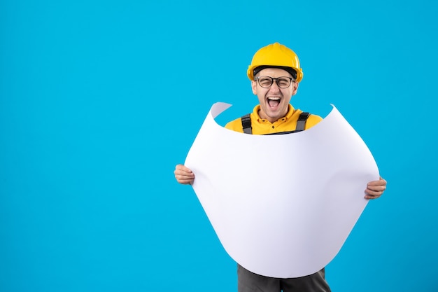 Free photo front view of male builder in yellow uniform with plan on blue