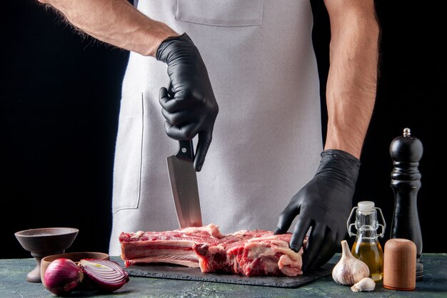 暗い表面で肉を切る正面図の男性の肉屋