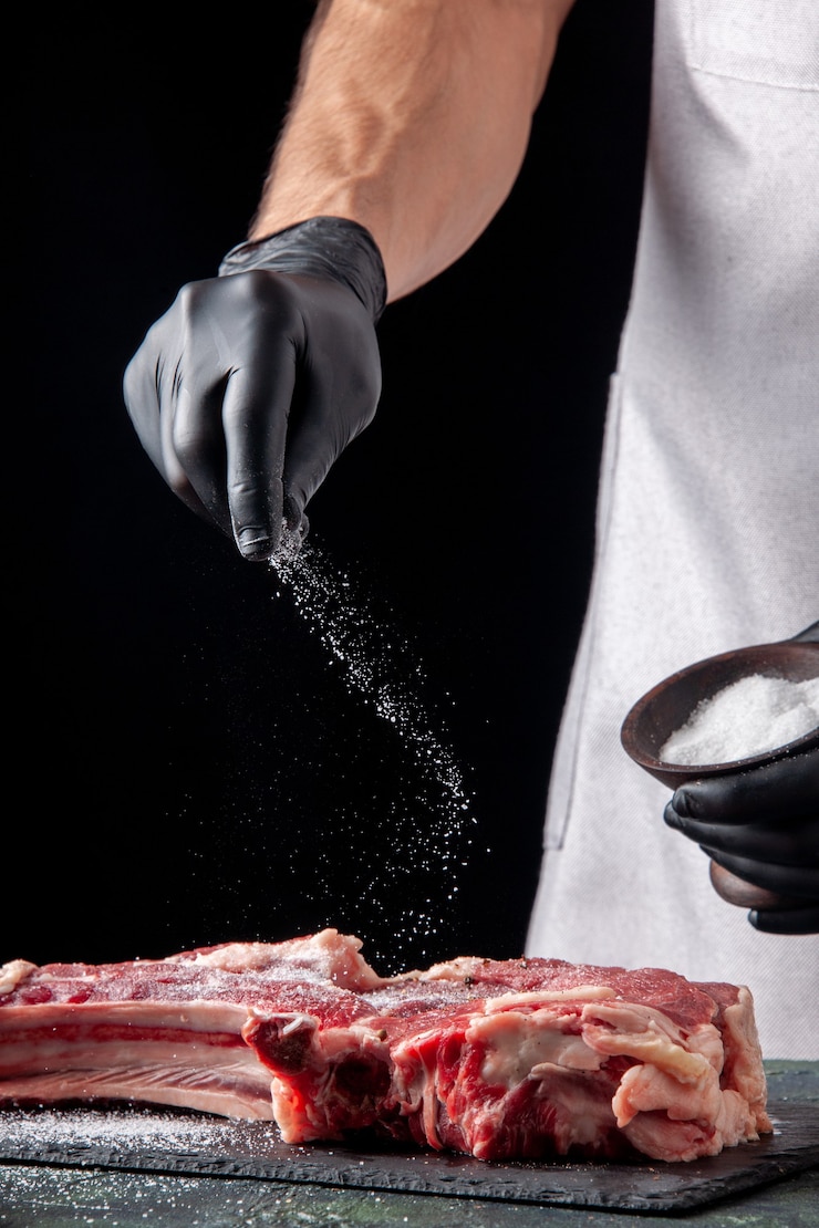 Free Photo front view male butcher salting meat on black surface