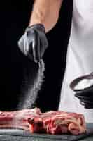 Free photo front view male butcher salting meat on dark surface